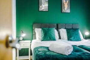 Lovely 3 Bed house - Park Lane في مانشستر: غرفة نوم خضراء بسرير مع جدار أخضر