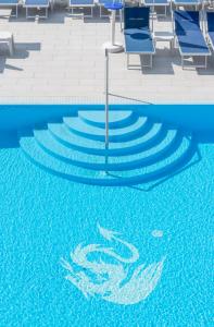 une piscine avec des chaises bleues et un dauphin peint sur l'eau dans l'établissement Hotel Drago - Garda Lake Collection, à Brenzone