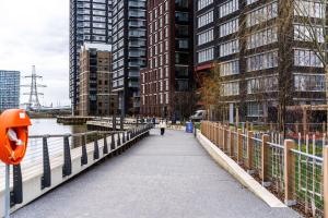 une personne marchant sur un pont sur une rivière avec des bâtiments dans l'établissement Livestay-Fabulous Three Bed Warehouse Conversion Apartment, à Londres