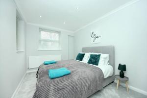 a bedroom with a large bed with blue pillows on it at Ealing Garden Flat in Ealing