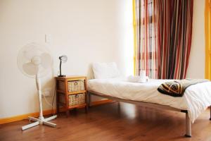 um quarto com uma cama, uma ventoinha e uma janela em Scalabrini Accommodation em Cidade do Cabo