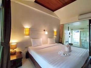 a bedroom with a large white bed with a window at Sandhana Samet Resort in Ko Samed