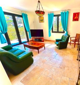 sala de estar con 2 sillas verdes y mesa en Grand appartement en face du village, en Moustiers-Sainte-Marie