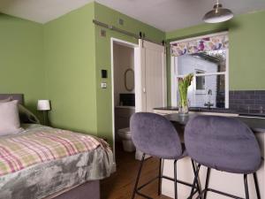 a bedroom with a bed and a table and two purple chairs at Stunning Studio in Corbridge, Northumberland in Corbridge