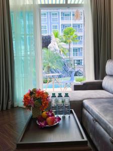 ein Wohnzimmer mit einem Tisch mit Obst und Wasserflaschen in der Unterkunft Grand Florida Pattaya By TheBest Management in Na Jomtien