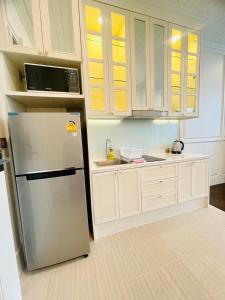 eine Küche mit einem Kühlschrank aus Edelstahl und weißen Schränken in der Unterkunft Grand Florida Pattaya By TheBest Management in Na Jomtien