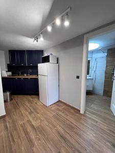 a kitchen with a white refrigerator and a wooden floor at Cabana B2 langa strandul Banffy in Topliţa