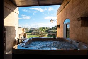a jacuzzi tub in a building with a window at Centre Island Holiday Home with private pool and hot tub in Kerċem