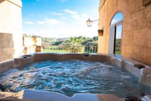 a large hot tub in a patio with water at Centre Island Holiday Home with private pool and hot tub in Kerċem