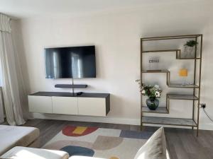 a living room with a flat screen tv on a wall at Hömli Close2City Apartment in Faygate