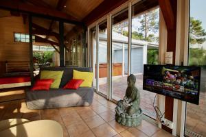 a screened in porch with a couch and a tv at Villa Patio + jacuzzi, FREE Surf+Body+Sup in Capbreton