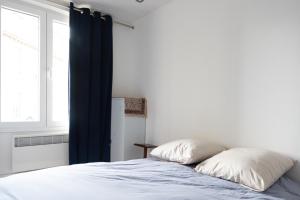 sypialnia z łóżkiem z niebieskimi zasłonami i oknem w obiekcie Bright and cozy apt in the heart of Belleville w Paryżu
