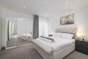 a white bedroom with a large bed and a mirror at Luxury Spacious Flat with Communal Gardens and Parking in London