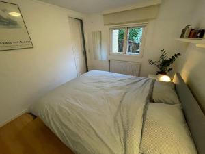 een slaapkamer met een wit bed en een raam bij Omheind prive 2 bedroom chalet VOORTHUIZEN VELUWE in Voorthuizen