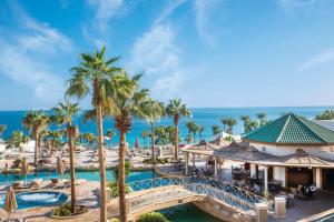 シャルム・エル・シェイクにあるPark Regency Sharm El Sheikh Resortのプールとヤシの木に架かる橋を持つリゾート