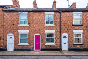 um edifício de tijolos com uma porta rosa e janelas em Stylish 2-Bed City-Centre Home in Chester by 53 Degrees Property - Ideal for Couples & Groups - Sleeps 6 em Chester