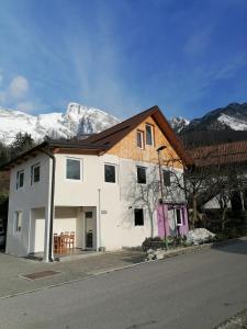 a white house with mountains in the background at Apartma Pr Urarj in Kobarid
