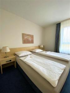 two large beds in a hotel room with a window at Fairway Hotel in Sankt Leon-Rot