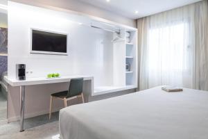 a bedroom with a bed and a desk and a tv at Hotel Macià Granada Five Senses Rooms & Suites in Granada