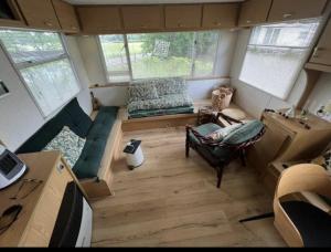 a small living room with a couch and a chair at Tiny House in de wei in Holten