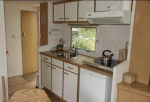 a kitchen with white cabinets and a sink and a window at Tiny House in de wei in Holten