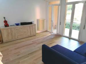 a living room with a blue couch and wooden floors at House Of Music in Gardone Riviera