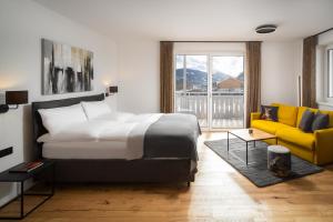 um quarto com uma cama e um sofá amarelo em Auhof - Apartments Bad Gastein em Bad Gastein