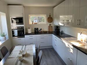 a kitchen with white cabinets and a table with a dining room at Å, the far end of Lofoten, top apartment. in Sørvågen