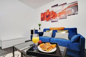 un salon avec un canapé bleu et une assiette de nourriture dans l'établissement Cosy appartement aux Portes de Paris, à Aubervilliers