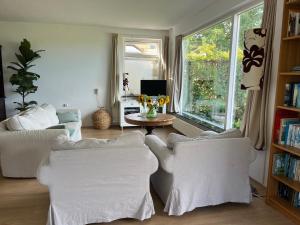 un soggiorno con 2 sedie bianche e un tavolo di huize Louwra a Egmond-Binnen