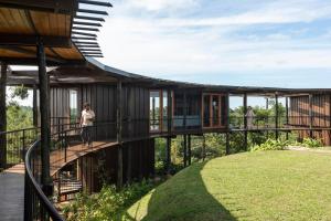 a wooden house with a balcony and a person standing on the deck at Trebartha East The Round House in Ahangama