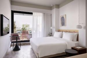 a hotel room with a large white bed and a window at The Social Athens Hotel, a member of Radisson Individuals in Athens