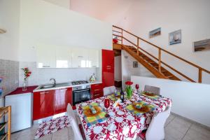 kuchnia ze stołem i kuchnia z czerwonymi szafkami w obiekcie Casa Vacanza sotto torre w mieście Calasetta