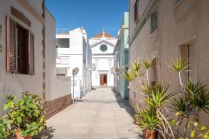 an alley with a building with a clock on it at Casa Vacanza sotto torre in Calasetta