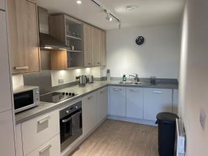 una cucina con armadi bianchi, lavandino e forno a microonde di stylish modern one bed Apartment a Birmingham