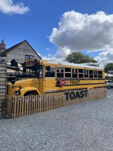 a yellow school bus parked next to a wooden fence at The Flyford in Worcester