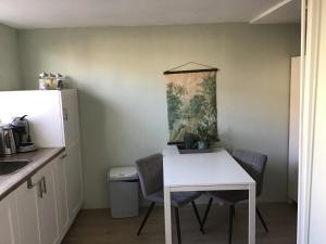 una pequeña cocina con mesa blanca y sillas en Life@Sea, en Zandvoort