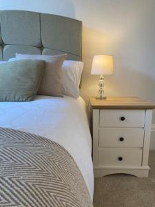 a bedroom with a bed and a nightstand with a lamp at Regency Apartment in Leamington Spa