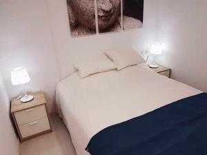 een slaapkamer met een wit bed en 2 lampen bij Lujoso apartamento en de la isla de puerto Marina in Benalmádena