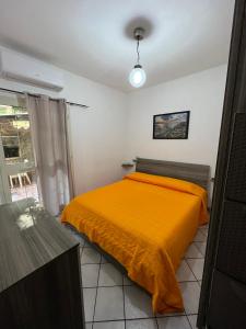 una camera con un letto e una coperta arancione di Casetta Vacanze a Santa Teresa di Gallura