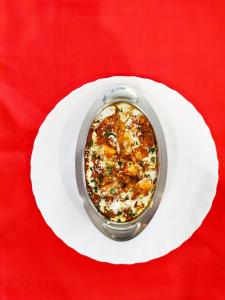 The Clovers Inn Boring Road في باتنا: وعاء من الطعام على طبق أبيض على طاولة حمراء