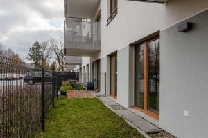 a white building with a fence next to a yard at Chill Apartments Marywilska in Warsaw