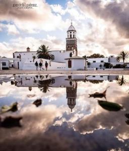 un reflejo de un edificio con una torre de reloj en Home from Home 2, en Teguise