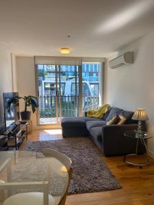 ein Wohnzimmer mit einem Sofa und einem TV in der Unterkunft Bayside Melbourne Apartment in Melbourne