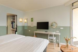 Schlafzimmer mit einem Bett, einem Schreibtisch und einem TV in der Unterkunft Hotel De Vossemeren by Center Parcs in Lommel