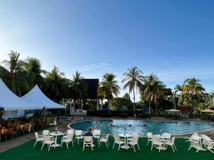 a pool with tables and chairs and palm trees at THE CLOVE MONT HOTEL in Kampung Gurun