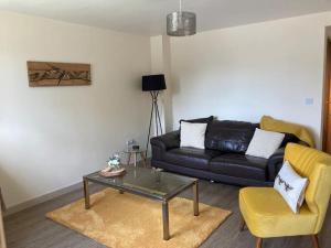 a living room with a black couch and a yellow chair at Delightful 2 bedroom house between Bristol & Bath in Warmley