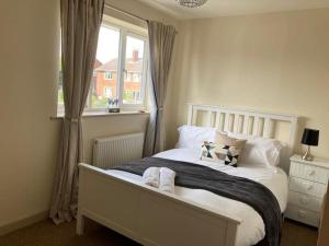 a bedroom with a white bed with pillows and a window at Delightful 2 bedroom house between Bristol & Bath in Warmley