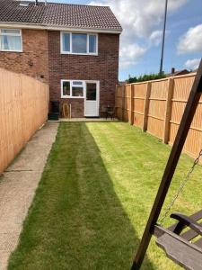 un patio trasero con una valla y una casa en Delightful 2 bedroom house between Bristol & Bath, en Warmley