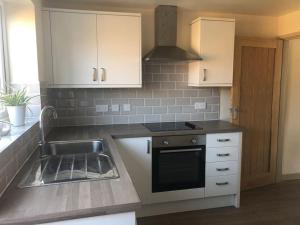 a kitchen with a sink and a stove at Delightful 2 bedroom house between Bristol & Bath in Warmley